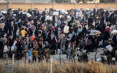 Syrians carry belongings back to the city center of the Syrian town of Tal Abyad, as seen from Turkey at the Turkish crossing of Akcakale in the southeast Sanliurfa province, on June 13, 2015. (AFP PHOTO / BULENT KILIC)