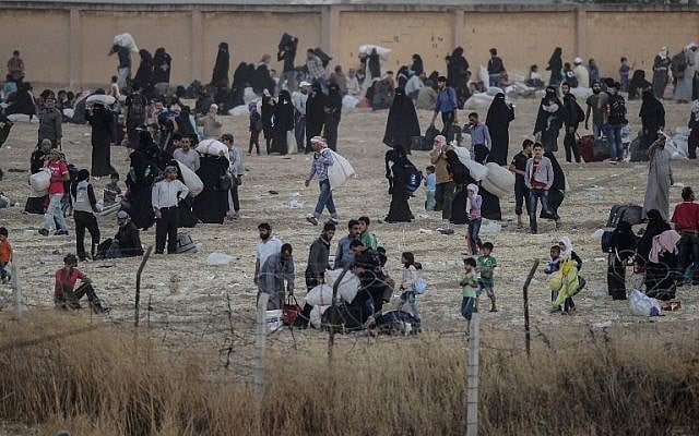 Syrians gather after leaving the city center of the Syrian town of Tal Abyad, as seen from Turkey at the Turkish crossing of Akcakale in the southeast Sanliurfa province, on June 13, 2015. (AFP PHOTO / BULENT KILIC)