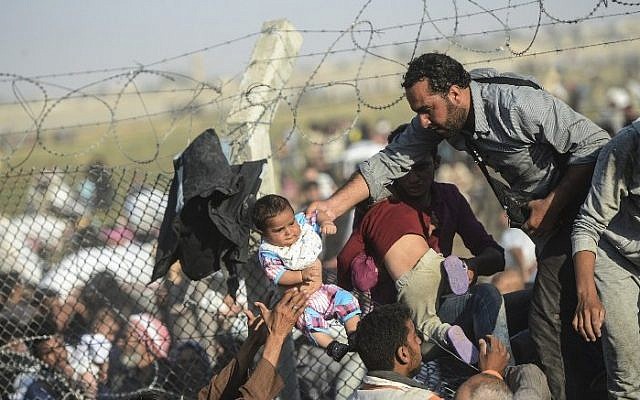 Syrians fleeing the civil war pass through broken border fences and trenches to enter Turkish territory illegally, near the Turkish border crossing at Akcakale in Sanliurfa province on June 14, 2015. (AFP/BULENT KILIC) Syrians fleeing the civil war pass through broken border fences and trenches to enter Turkish territory illegally, near the Turkish border crossing at Akcakale in Sanliurfa province on June 14, 2015. (AFP/BULENT KILIC)