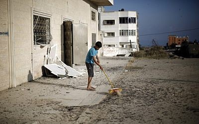 A Palestinian boy cleans debris near a training base of the Ezzedine al-Qassam brigades, the military wing of Hamas, in Gaza City, after Israeli warplanes struck multiple targets on June 4, 2015, in response to Palestinian rocket fire. (AFP/MOHAMMED ABED)