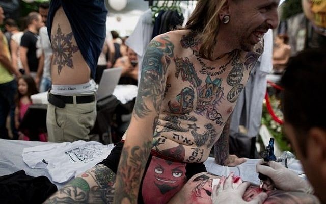 An artist tatooes a man's leg during the three-day annual tattoo festival on June 6, 2015 in Tel Aviv (Menahem Kahana/AFP)