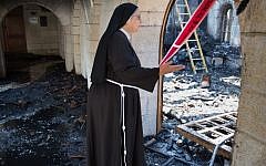 A nun inspects the damage at the Church of the Multiplication at Tabgha, on the shores of the Sea of Galilee in northern Israel,  June 18, 2015. (AFP Photo/Menahem Kahana)