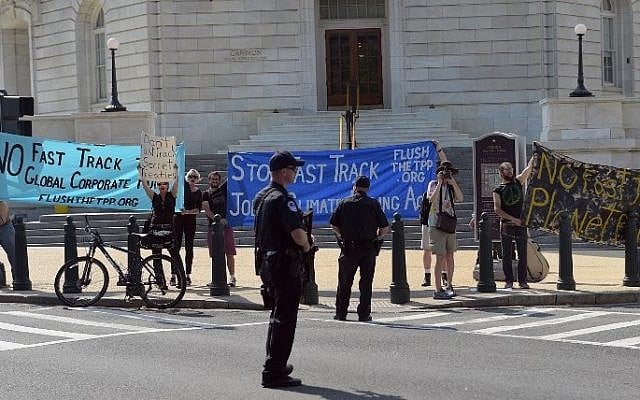 Anti-trade protestors hold banners outside of the Cannon House Office Building as US President Barack Obama arrived on Capitol Hill to lobby House Democrats on June 12, 2015 in Washington, DC.  The House blocked a trade bill on June 12 which would have given Obama authority to pursue a sweeping free trade agenda. (AFP PHOTO/Mandel NGAN)