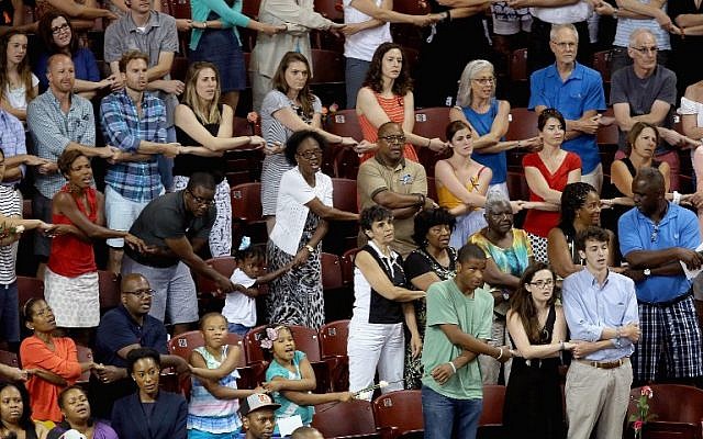 Thousands of people hold hands and sing 'We Shall Overcome' during a prayer vigil for the nine victims of the Emanuel AME Church shooting at the College of Charleston TD Arena June 19, 2015 in Charleston, South Carolina (Chip Somodevilla/Getty Images/AFP)