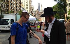 Illustrative: A Chabad representative lays phylacteries on a passerby in New York's Union Square on Friday, June 19, 2015 (Facebook)