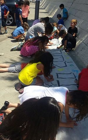 Students and teachers create signs on June 30, 2015 to cover the racist graffiti spray painted on their school's walls the night before. (Courtesy: Hand in Hand) Students and teachers create signs on June 30, 2015 to cover the racist graffiti spray painted on their school's walls the night before. (Courtesy: Hand in Hand)