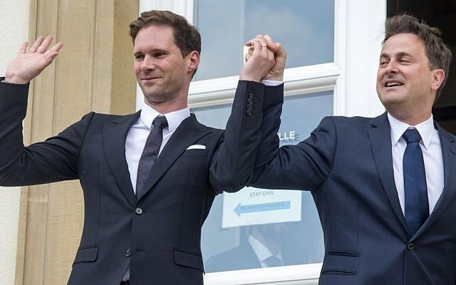 Luxembourg's Prime Minister Xavier Bettel, right, holds up the hand of his partner Gauthier Destenay, with a wedding band on his finger, as they leave the town hall after their marriage in Luxembourg, on Friday, May 15, 2015 (AP/Charles Caratini)