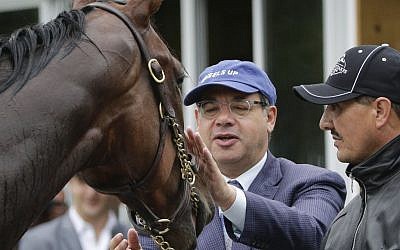 Ahmed Zayat, left, owner of Kentucky Derby and Preakness Stakes winner American Pharoah, approaches the horse as he is held for a bath by hot walker Juan Ramirez after a workout at Belmont Park, Friday, June 5, 2015, in Elmont, New York (AP Photo/Julie Jacobson)