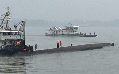 Rescue workers stand on the capsized ship, center, on the Yangtze River in central China's Hubei province Tuesday, June 2, 2015. (Chinatopix/AP)