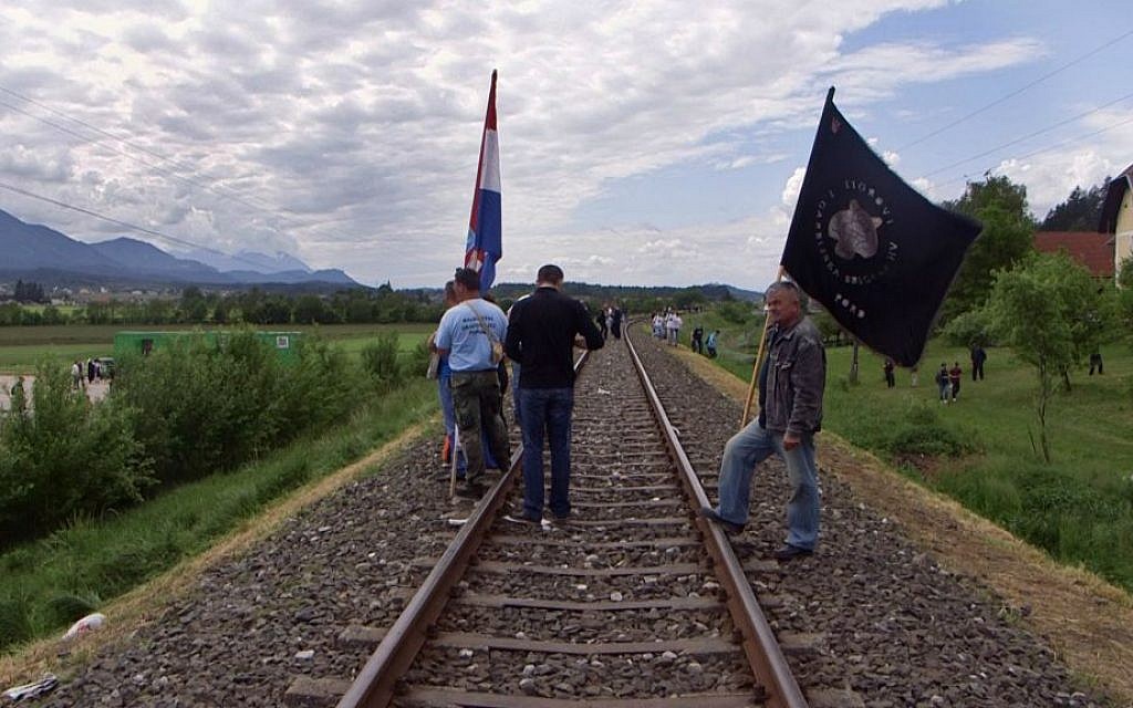 In this May 16, 2015 photo, men from Croatia stand on railway tracks as they attend a memorial to the thousands of victims of the mass killings by Yugoslav communists, in Bleiburg, Austria. (AP Photo/Darko Bandic)