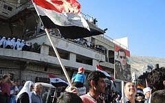 A man holds a Syrian flag and a poster of President Bashar Al Assad during a pro-Syrian army protest in Majdal Shams, June 2015. (Melanie Lidman/Times of Israel)