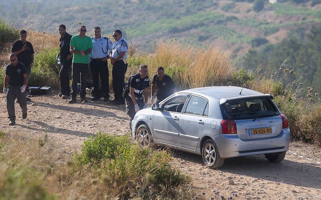 Israeli security officials stand near the car belonging to Israeli victims of an attack by a Palestinian terrorist near the Dolev settlement in the West Bank on June 19, 2015. (Flash90)