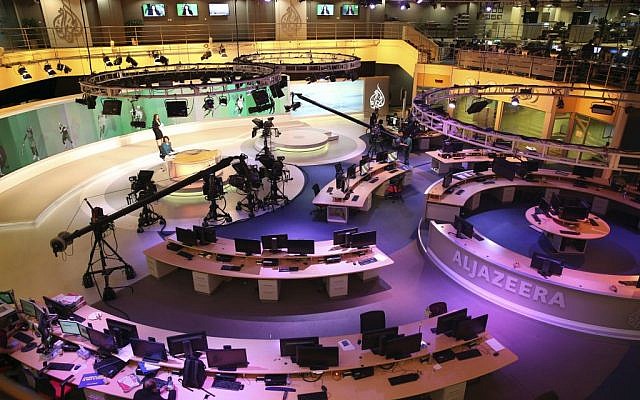 In this Jan. 1, 2015, file photo, staff members of Al-Jazeera International work at the news studio in Doha, Qatar. Ahmed Mansour, a prominent Al-Jazeera Arabic journalist, was detained Saturday, June 20, in Germany over an Egyptian arrest warrant, the Qatar-based broadcaster reported. (AP/Osama Faisal) 