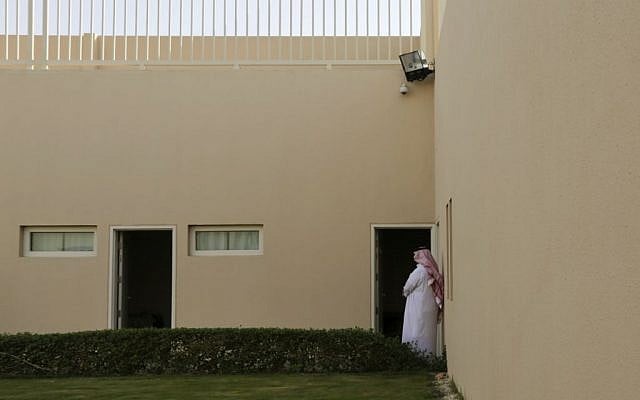 In this April 26, 2015, photo, a Saudi man stands in front of the door of an inmate room at the Mohammed bin Nayef Center for Advice, Counseling and Care. At the center, inmates called "beneficiaries" by staff are housed in a complex of low-rise buildings, whose resort-like appearance is belied by the concrete walls, barbed wire and armed guards that surround it. (AP Photo/Hasan Jamali)