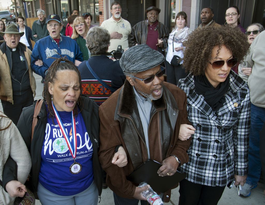 In this Friday, March 6, 2015, file photo, from left, Della Montgomery-Riggins, Charles Thornton and Spokane NAACP president Rachel Dolezal link arms and sing "We Shall Overcome" at a rally in downtown Spokane, Wash., responding to a racist and threatening package received by Dolezal. (Dan Pelle/The Spokesman-Review via AP, File) In this Friday, March 6, 2015, file photo, from left, Della Montgomery-Riggins, Charles Thornton and Spokane NAACP president Rachel Dolezal link arms and sing "We Shall Overcome" at a rally in downtown Spokane, Wash., responding to a racist and threatening package received by Dolezal. (Dan Pelle/The Spokesman-Review via AP, File)