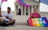 Carlos McKnight, 17, of Washington, left, and Katherine Nicole Struck, 25, of Frederick, Md., hold flags in support of gay marriage as security walks behind outside of the Supreme Court in Washington DC, Friday, June 26, 2015. (AP/Jacquelyn Martin)