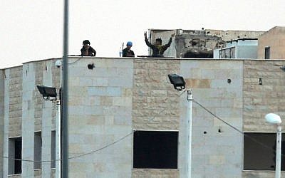 In this photo taken from the Turkish side of the border between Turkey and Syria, in Akcakale, southeastern Turkey, Kurdish fighters wave and flash the V-sign as the hold their positions atop pf a building in the outskirts of Tal Abyad, Syria, Monday, June 15, 2015 (AP Photo/Lefteris Pitarakis)
