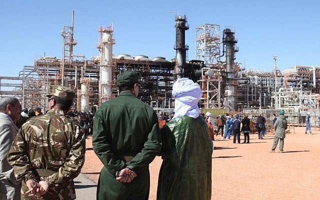 Algerian soldiers and officials stand in front of a gas plant in Ain Amenas where dozens were killed during a hostage taking, seen in background, during a visit organized by the Algerian authorities for news media, January 31, 2013. (AP, File) 