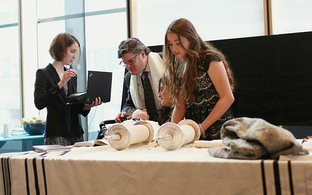 Jacob Trossman's friend Hannah Sandler (right) prepares to chant from the Torah as he recites the blessings using a Blink Switch as his parents (center) look on. Toronto, May 18, 2015. (Nechama Laitman Photography)