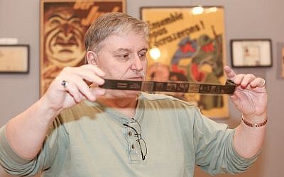 Darrell English, founder of the New England Holocaust Institute & Museum, has amassed 3,000 objects connected to the Shoah during 40 years of buying, selling and trading artifacts. Here, English examines an original Nazi propaganda filmstrip related to the 'T4' euthanasia program, one item in his Massachusetts-based collection. (photo credit: Elan Kawesch/The Times of Israel)