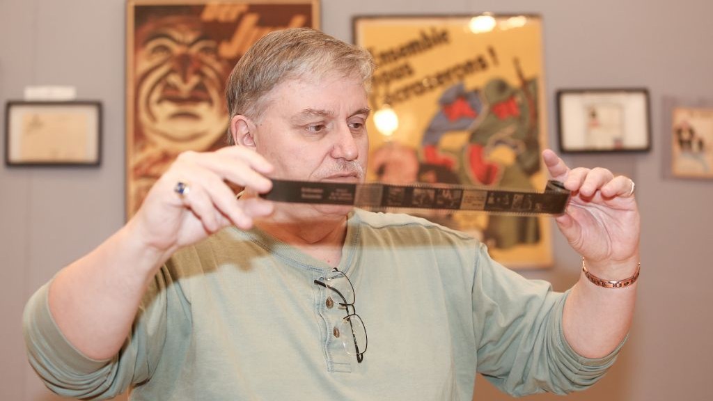 Darrell English, founder of the New England Holocaust Institute & Museum, has amassed 3,000 objects connected to the Shoah during 40 years of buying, selling and trading artifacts. Here, English examines an original Nazi propaganda filmstrip related to the 'T4' euthanasia program, one item in his Massachusetts-based collection. (photo credit: Elan Kawesch/The Times of Israel) Darrell English, founder of the New England Holocaust Institute & Museum, has amassed 3,000 objects connected to the Shoah during 40 years of buying, selling and trading artifacts. Here, English examines an original Nazi propaganda filmstrip related to the 'T4' euthanasia program, one item in his Massachusetts-based collection. (photo credit: Elan Kawesch/The Times of Israel)