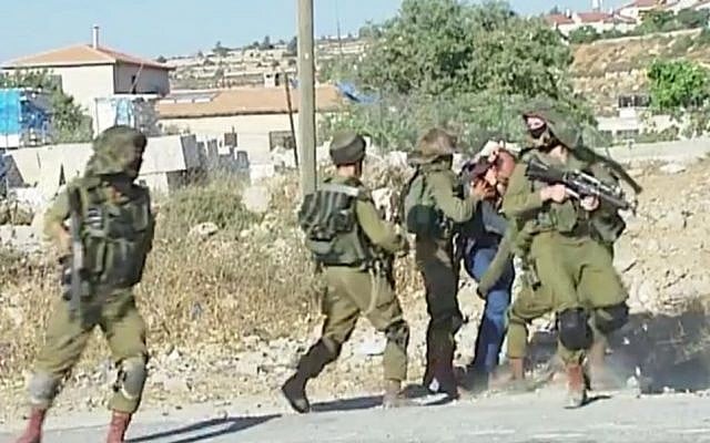A Palestinian man is beaten and restrained by IDF soldiers during a violent demonstration in the Jelazoun refugee camp, near Ramallah, on June 12, 2015. (screen capture: Palestine TV)