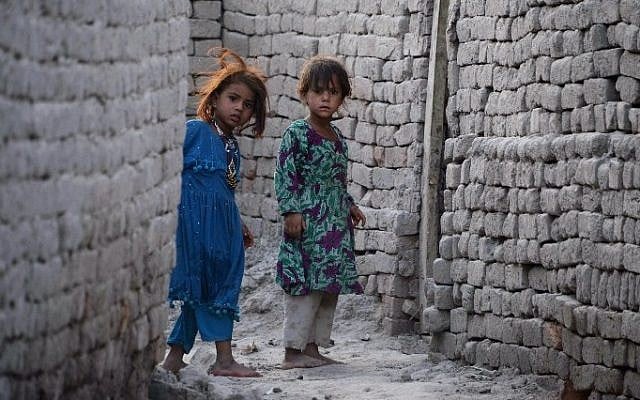 In this July 5, 2015 photo, Afghan girls who fled from Kot district of the eastern Nangarhar' province, following threats from the Islamic State group to leave their homes, look around a corner next to their temporary homes in Jalalabad. (AFP/ Noorullah Shirzada)