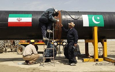 Illustrative: Iranian laborers work on a section of a pipeline  adorned with Iranian (L) and Pakistan (R) flags in the Iranian border city of Chah Bahar. March 11, 2013 (AFP PHOTO / ATTA KENARE / FILES)