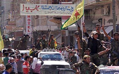 File: Kurdish People's Protection Units (YPG) fighters wave their movement's flag and cheer as they parade in the northeastern Syrian town of Qamishli after returning from battling Islamic State group jihadists in Tal Abyad on the border with Turkey, June 24, 2015. (AFP/Delil Souleiman)