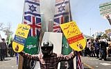 An Iranian protester holds placards as he stands in front of prints of Israeli, US, British and Saudi Arabian flags during a demonstration to mark the Quds (Jerusalem) International day in Tehran on July 10, 2015. (AFP/ ATTA KENARE)