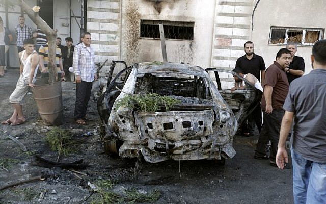 Palestinians gather around a burnt-out car in Gaza City on July 19, 2015, after explosions destroyed five cars in Gaza belonging to members of Hamas and Islamic Jihad, witnesses and a security source said, amid tensions between the Palestinian territory's rulers and Islamist extremists. (AFP/MOHAMMED ABED)