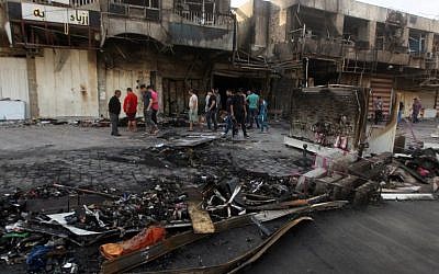 Iraqi men gather outside a burnt shop in Baghdad on July 22, 2015 following two late night car bombs which killed at least 19 people in mostly Shiite neighborhoods of the Iraqi capital, according to police. (AFP PHOTO/ AHMAD AL-RUBAYE)