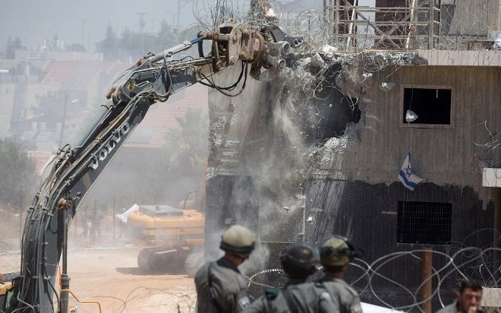 Israeli security forces stand guard as bulldozers, under an Israeli High Court ruling, start the demolition of the so-called Dreinoff buildings in the settlement of Beit El, north of Ramallah in the West Bank, on 29 July, 2015. (AFP/ MENAHEM KAHANA)