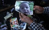 A man shows a picture of 18-month-old Palestinian toddler Ali Saad Dawabsha, who died when his family house was set on fire by alleged Jewish extremists in the West Bank village of Duma, on July 31, 2015. (AFP/Jaafar Ashtiyeh)