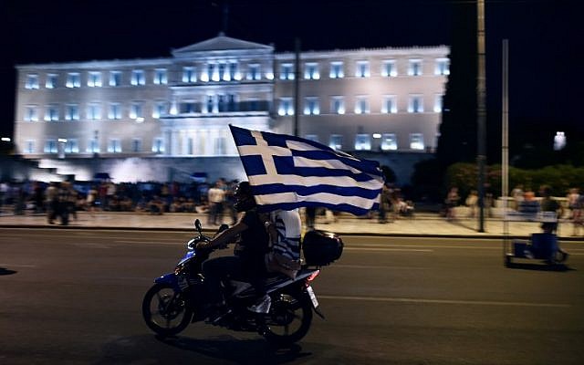 A motorcyclist with his passenger holding a Greek flag passes in front of the Greek Parliament in Athens on July 5, 2015, after early results showed those who rejected further austerity measures in a crucial bailout referendum were poised to win. (AFP/ARIS MESSINIS) A motorcyclist with his passenger holding a Greek flag passes in front of the Greek Parliament in Athens on July 5, 2015, after early results showed those who rejected further austerity measures in a crucial bailout referendum were poised to win. (AFP/ARIS MESSINIS)