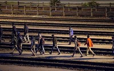 Migrants walk along railway tracks at the Eurotunnel terminal on July 28, 2015 in Calais-Frethun. (AFP PHOTO / PHILIPPE HUGUEN)