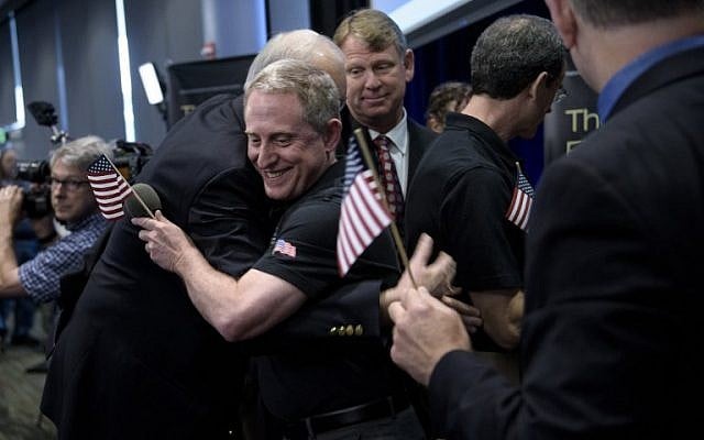 Dr. Allan Stern, principal investigator for NASA's New Horizons mission, gets a hug while others celebrate the closest fly-by of Pluto by the New Horizons probe at the Johns Hopkins University Applied Physics Laboratory July 14, 2015 in Laurel, Maryland. (AFP PHOTO/BRENDAN SMIALOWSKI)