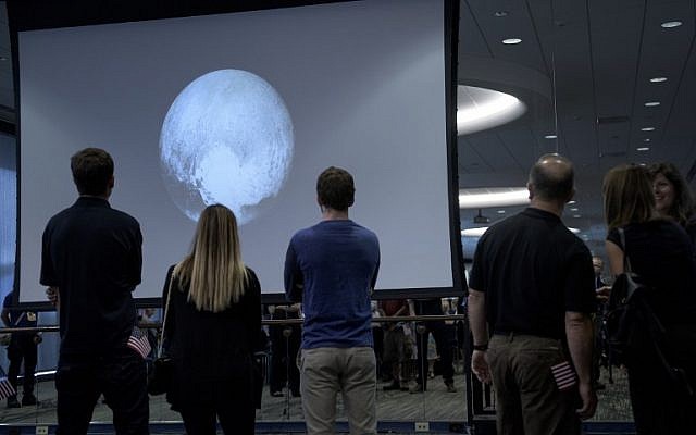 People look at an early image of Pluto taken by the New Horizons probe as the craft makes its closest fly-by of the dwarf planet at the Johns Hopkins University Applied Physics Laboratory July 14, 2015 in Laurel, Maryland.(AFP PHOTO/BRENDAN SMIALOWSKI)