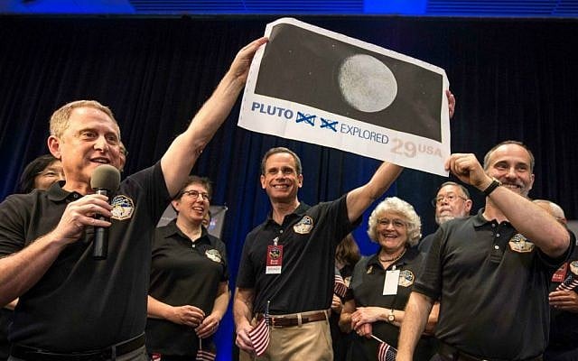 In this photo provided by NASA, New Horizons Principal Investigator Alan Stern of Southwest Research Institute (SwRI), Boulder, Colo., left, Johns Hopkins University Applied Physics Laboratory (APL) Director Ralph Semmel, center, and New Horizons Co-Investigator Will Grundy of the Lowell Observatory hold a print of a US stamp with their suggested update since the New Horizons spacecraft made its closest approach to Pluto, at the Johns Hopkins University Applied Physics Laboratory (APL) in Laurel, Md. on Tuesday, July 14, 2015. (Bill Ingalls/NASA via AP)