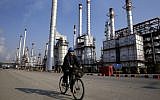 An Iranian oil worker rides his bicycle near an oil refinery south of the capital, Tehran, December 22, 2014. (AP/Vahid Salemi/File)