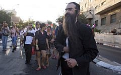 Yishai Schlissel pictured as he walks through a Gay Pride parade and is just about to pull a knife from under his coat and start stabbing people in Jerusalem, Thursday, July 30, 2015. (AP Photo/Sebastian Scheiner)