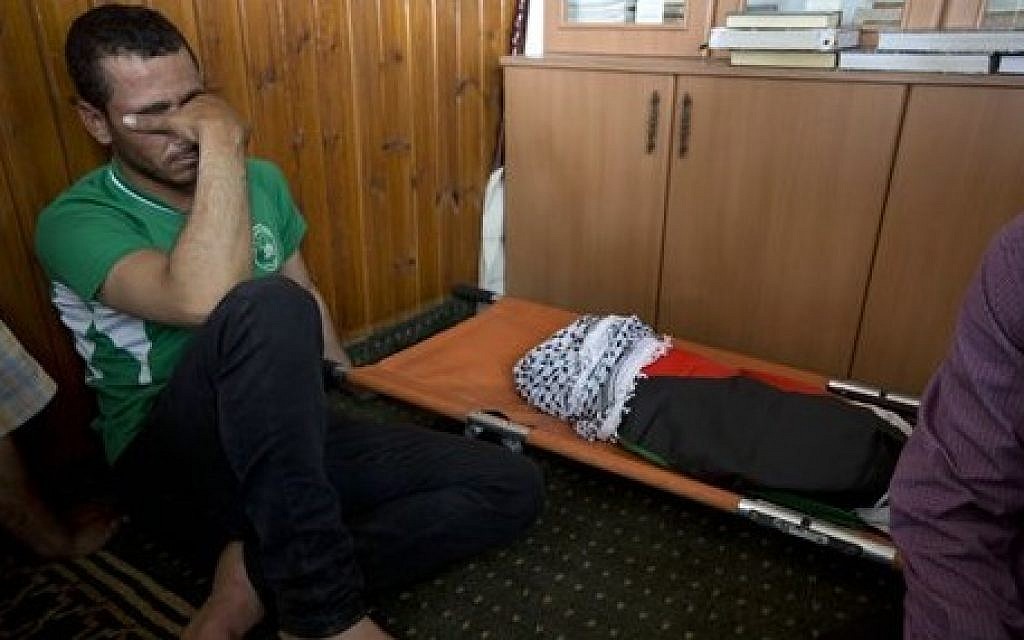 A Palestinian man mourns alongside the body of a one-and-a-half year old boy, Ali Dawabsha, during his funeral in Duma village near the West Bank city of Nablus, Friday, July 31, 2015. (Majdi Mohammed/AP)