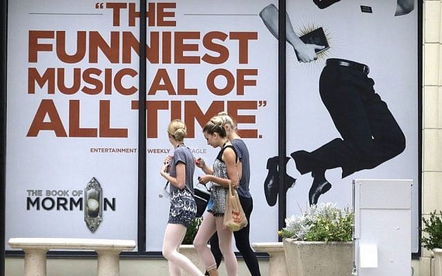 People walk past signs announcing the "Book of Mormon" musical at the Capitol Theatre, Monday, July 27, 2015, in Salt Lake City. (AP Photo/Rick Bowmer)
