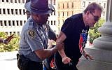 In this July 18, 2015 photo provided by Rob Godfrey, police officer Leroy Smith, left, helps a man wearing National Socialist Movement attire up the stairs during a rally in Columbia, South Carolina. (Rob Godfrey via AP, file)