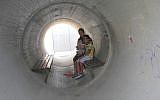 Devorah Israeli, of Nitzan, with 8-year-old Idan and 6-month-old Ron in the sewage pipe bomb shelter next to her caravilla during Operation Protective Edge in summer 2014. (Melanie Lidman/Times of Israel)