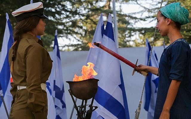Adi Kaplan, widow of Captain Zvi (Zvika) Kaplan killed in Operation Protective Edge, lights a torch during a ceremony marking one year since the war at the Mount Herzl military cemetery in Jerusalem on July 6, 2015. (Gili Yohanan/POOL/Flash90) 