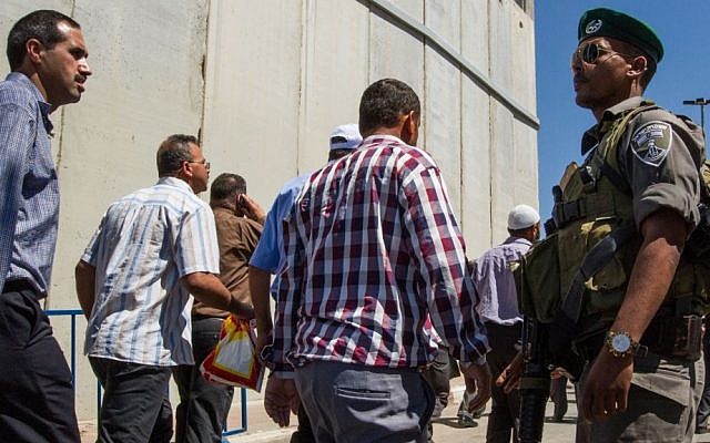 A soldier looks on as men walk through Checkpoint 300 between Bethlehem and Jerusalem on the last Friday of Ramadan on July 10, 2015 Micah Bond/Flash90