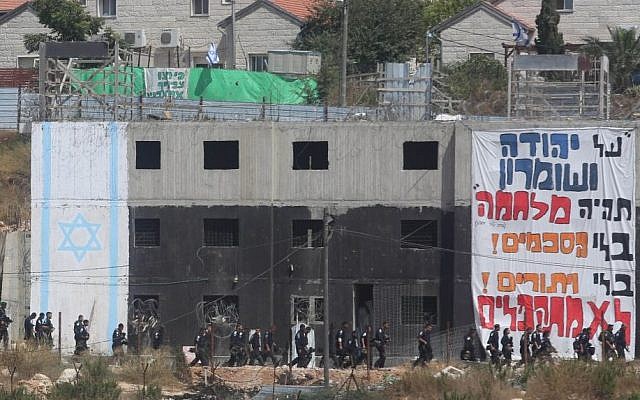 Israeli security forces walk by a building in which Israeli settlers had barricaded themselves to resist an evacuation at the Jewish settlement of Beit El, near the West Bank town of Ramallah, July 28, 2015. (FLASH90)