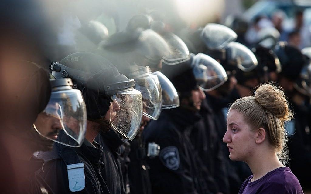 Israeli security forces stand opposite a Jewish settler amid the demolition of illegally constructed buildings, at the Jewish settlement of Beit El, near the West Bank town of Ramallah, on July 28, 2015 (Nati Shohat/FLASH90)