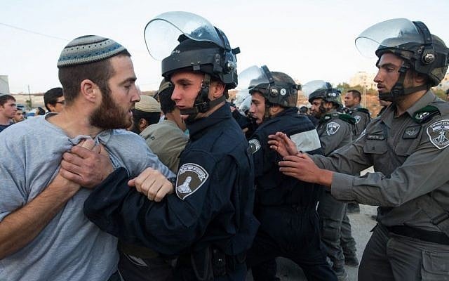 Israeli security forces scuffle with settlers who had barricaded themselves in an attempt to prevent the demolition of illegally constructed buildings, at the Jewish settlement of Beit El, near the West Bank town of Ramallah, on July 28, 2015 (Nati Shohat/FLASH90)